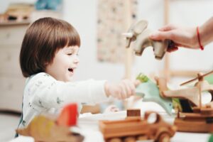 Smiling child playing and exploring with wooden toys in a bright room, fostering creativity.